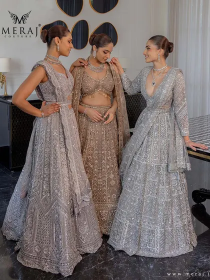 A candid moment between models wearing the silver and gold lehengas, showing how these outfits look natural and elegant.