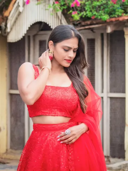 A model in a vibrant red lehenga-style gown. The all-over texture and matching tulle dupatta make this a great option for a modern bride or a festive party.
