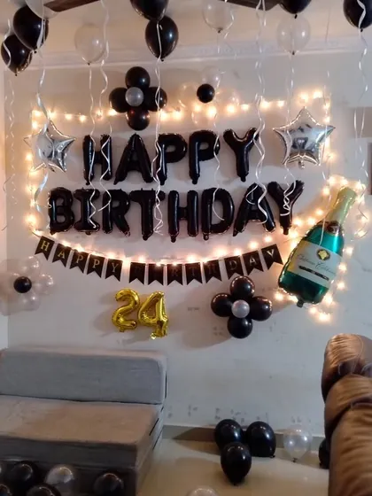 A stylish black and silver themed birthday wall decoration with fairy lights.