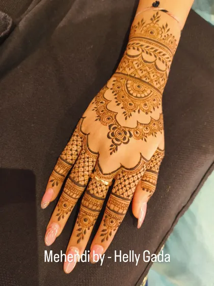 A stunning back-hand design with a scalloped edge and a mandala-like center. The fingers are adorned with a mix of net and band patterns, creating a very full and traditional look.