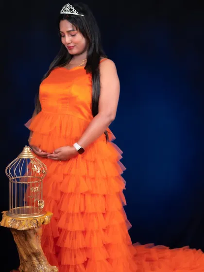 This vibrant orange ruffle gown is perfect for making a bold statement. It's shown here with a tiara for a royal-themed maternity studio shoot.