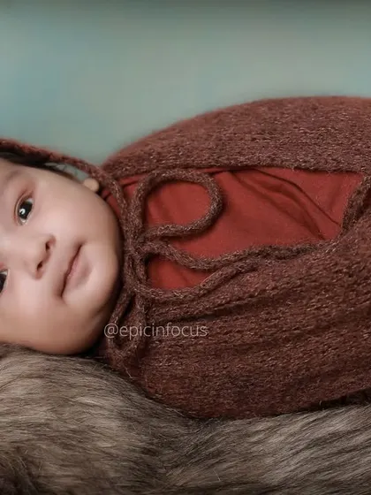 A close up of a swaddled two-month-old baby looking calmly at the camera. These shots focus on their developing features and expressive eyes.