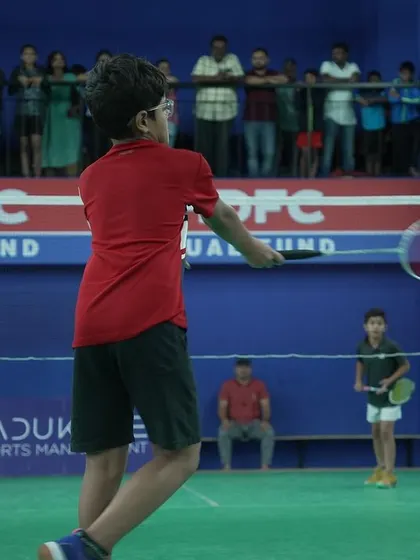 A young player in action with spectators watching from the gallery above. Our tournaments at venues like PDCSE offer a professional viewing experience.
