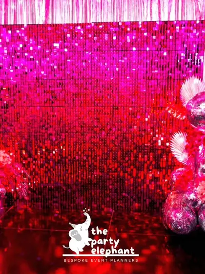 A shimmering pink sequin wall served as the perfect photo backdrop for the disco party, flanked by poodle-shaped sculptures made of disco balls and feathers for a touch of retro glam.