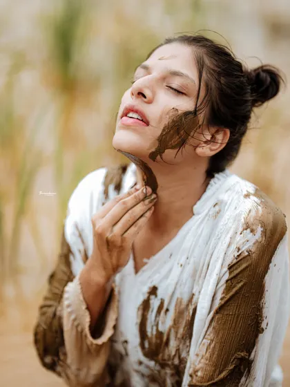 A close-up shot focusing on the texture of the mud on the model's skin. This type of detail shot adds a sensory element to the photo series.