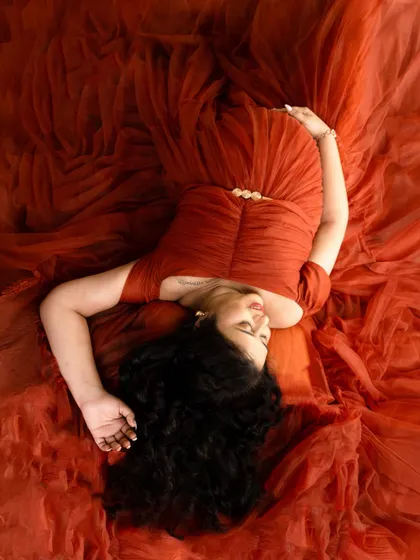 A beautiful top-down shot lying on a bed of rich, rust-colored tulle. This artistic angle creates a stunning, textured portrait.