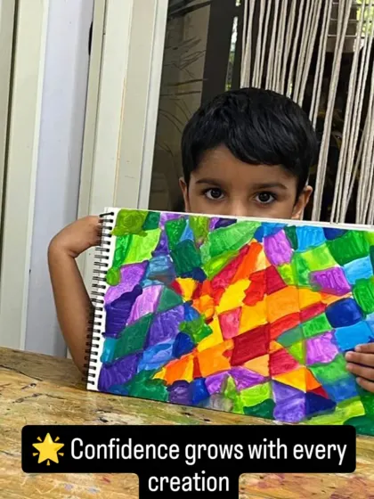Confidence grows with every creation. This student is peeking over her colorful abstract artwork, a testament to the courage it takes to express oneself through art.