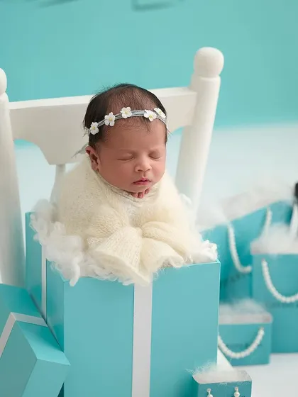 A luxurious, Tiffany-inspired theme, with a newborn sleeping in a signature blue box, surrounded by pearls and gift bags.