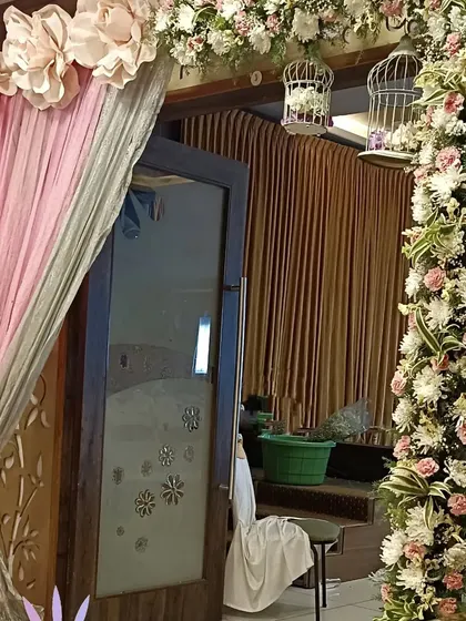 A charming entrance decoration featuring a floral arch with hanging birdcages. The soft pink and silver drapes add a touch of whimsy and elegance.