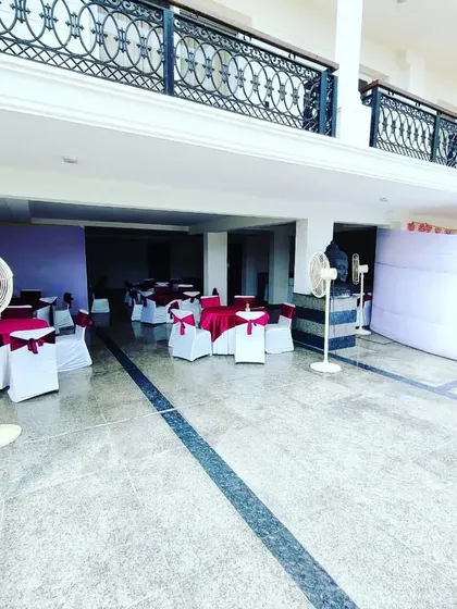A wider view of an event space we prepared, showing the arrangement of pedestal fans for ventilation, guest seating tables, and a partition for the catering area in a semi-open venue.