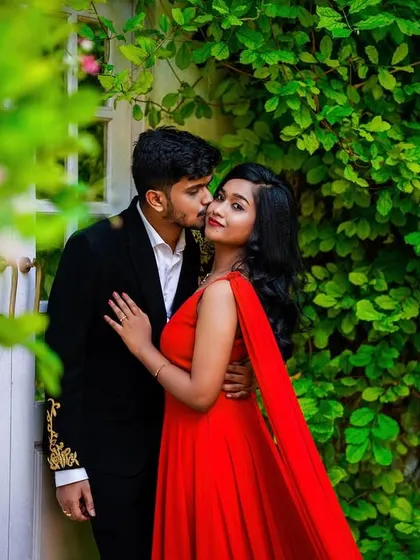 A romantic kiss on the cheek against a wall of green ivy.