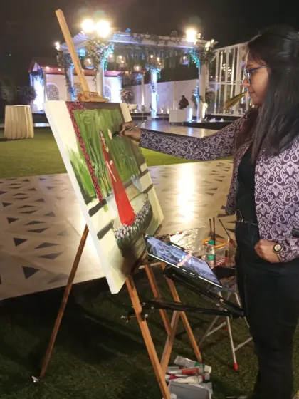 A side view of me painting at an outdoor event, showing my concentration and the tools of my trade: my easel, canvas, and palette.