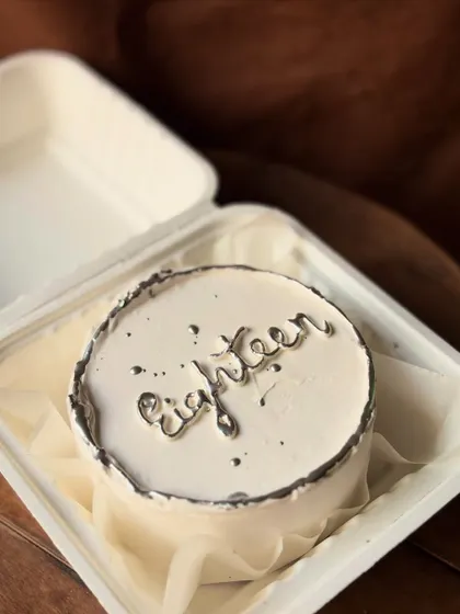 An elegant and modern bento cake for an eighteenth birthday. The white cake is decorated with a silver "eighteen" and a metallic silver border for a touch of glam.