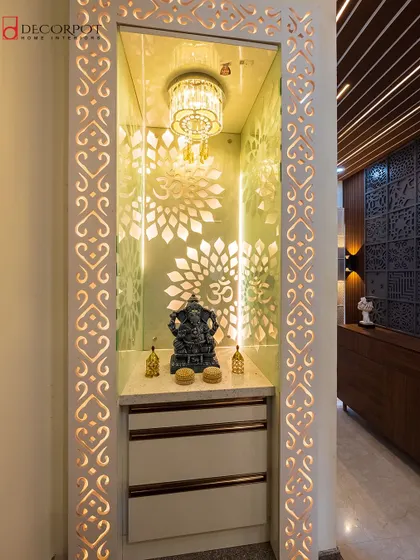 This magnificent pooja unit features an intricately cut jali frame with backlighting. The grand chandelier inside adds a touch of opulence to the sacred space.