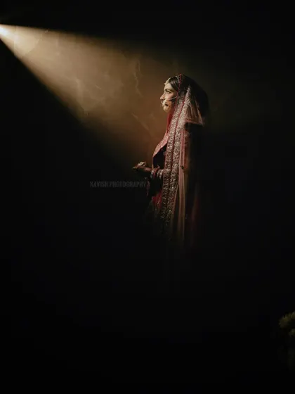 A solitary bridal portrait using dramatic spotlighting. The bride is captured in profile, creating a sense of anticipation and quiet beauty before the ceremony.