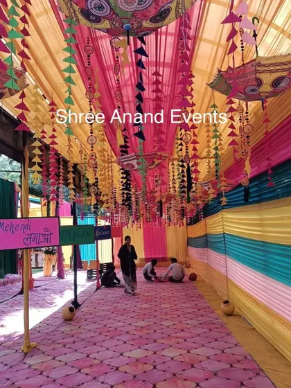 The entrance to a Mehndi ceremony, decorated with colorful drapes, hanging tassels, and traditional Rajasthani umbrellas.