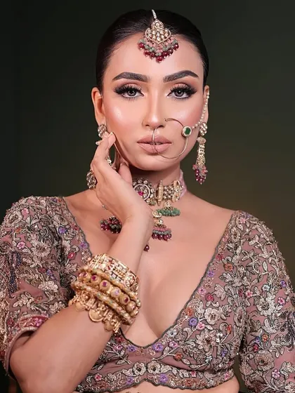 This exquisite bridal set features a polki choker with ruby and emerald drops, paired with matching bangles, nath, and maang tikka for a complete royal look.