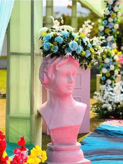 An artistic decor element featuring a pink bust used as a vase for a beautiful blue and white floral arrangement. It's these unique details that make an event memorable.