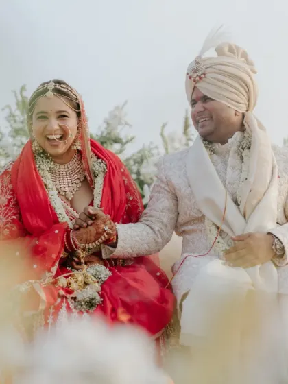 A joyful moment of the couple holding hands and laughing during their wedding ceremony on the sand dunes.