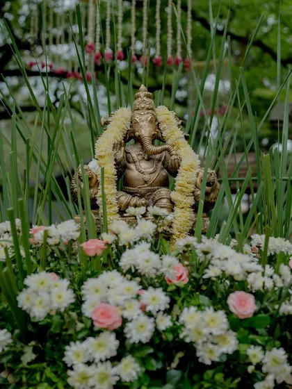 A Ganesha idol surrounded by white and pink flowers.