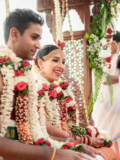 The couple sits on a traditional swing (oonjal), a beautiful and significant ritual in South Indian weddings. Their smiles reflect the happiness of the moment.