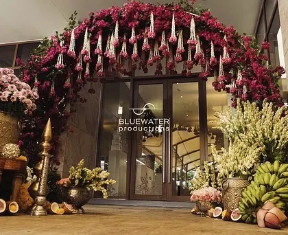 The complete entrance vignette, with the lush floral arch flanked by traditional brass pots and arrangements of tuberoses and bananas.