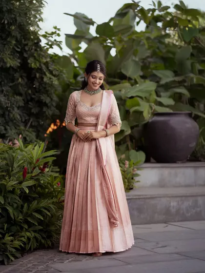 A soft and elegant pastel pink half saree. The pleated silk skirt is paired with a beautifully embroidered blouse, creating a look of effortless sophistication.