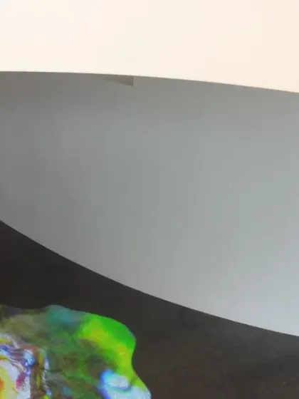 A close-up detail of the 'Amorphous Color Rain' projection at the Novartis Campus. The abstract, colorful forms flow across the floor, creating a liquid-like image that contrasts with the solid granite.
