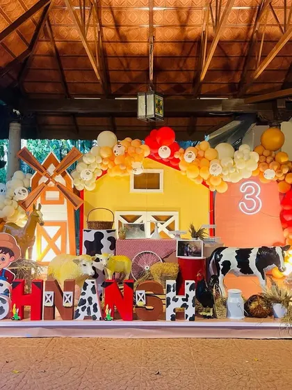 An adorable barnyard-themed party for a third birthday. The setup includes a red barn, a windmill, and friendly farm animals.