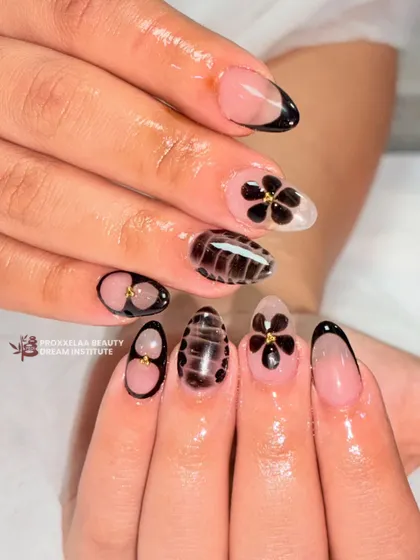 A chic and sophisticated design featuring a mix of styles. I combined a modern black French tip, hand-painted black flowers with gold centers, and a unique textured pattern.