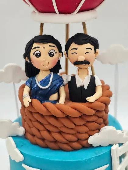A heartwarming anniversary cake featuring a couple in a hot air balloon. My classes cover creating personalized couple figurines that capture their likeness and style, like this traditional Indian attire.
