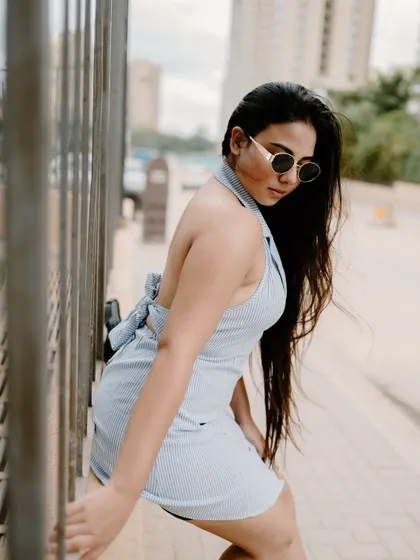 A stylish portrait of a model leaning against a fence in the city. Her pose and the urban architecture create a chic and modern fashion image.