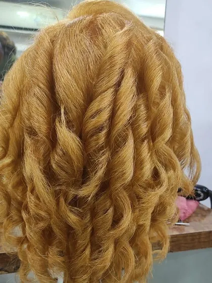 A view from the back of a student's curl styling practice. This shows the uniformity and definition they learn to create, which is essential for professional work.