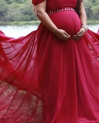 A close-up of a client's baby bump in a red maternity gown.