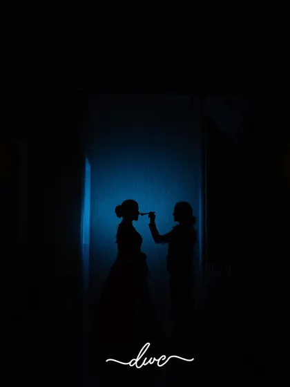 A creative silhouette of the bride getting her makeup done, the dramatic lighting turning a simple moment into a piece of art.