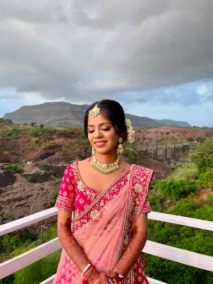A destination wedding look for this bride in a pink lehenga. The makeup is soft and romantic, perfect for the scenic mountain backdrop.