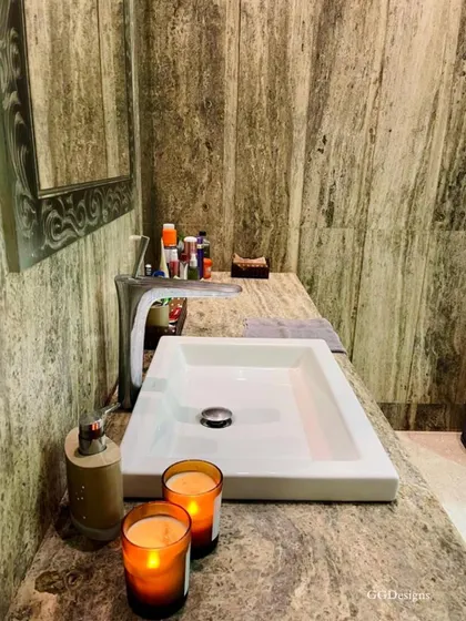 A close-up of the silver travertine marble used in this bathroom. The natural, earthy pattern of the stone adds texture and a sense of calm, complemented by simple decor like scented candles for a spa-like ambiance.