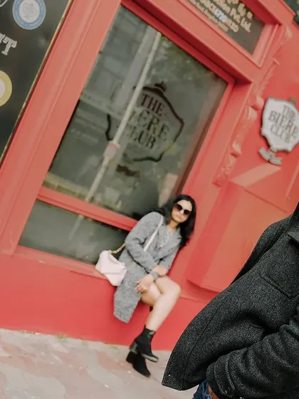 A creative, angled shot of a couple posing outside a red-walled pub, creating a dynamic and edgy urban photo.