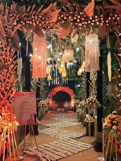 The entrance to the bohemian reception, featuring a walkway flanked by pampas grass and leading to a seating area with macrame and wicker details. It sets a relaxed and chic vibe.