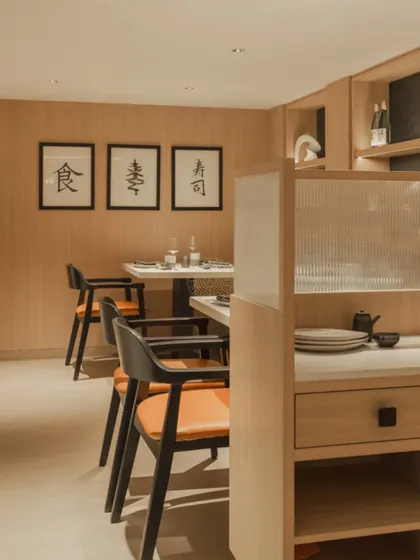 The seating in the downstairs area is intimate and cozy, with wood-paneled walls, simple framed calligraphy, and fluted glass partitions for privacy.