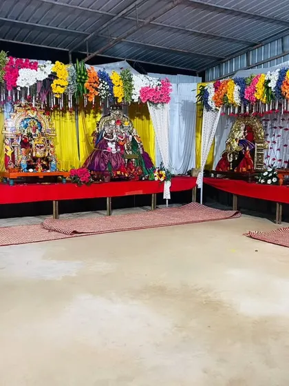 A closer view of the festival stage, showing the individual deity setups with vibrant yellow backdrops and colorful floral arrangements.