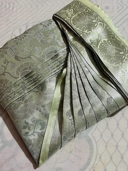 A soft, sage green Banarasi saree with its pleats set. This is a great example of how my service can prepare even heavy, ornate sarees for easy draping.