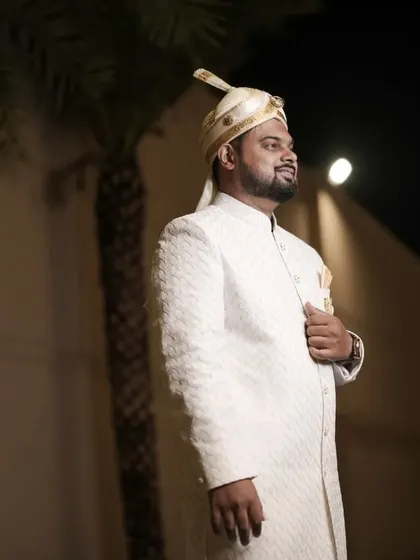 A handsome portrait of the groom in his white sherwani and turban, looking sharp and ready for the reception.