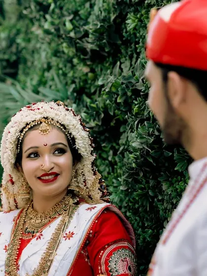The look of love and admiration. This candid shot captures a beautiful moment between a Marathi bride and groom during their wedding ceremony. Her traditional 'mundavalya' and his 'pheta' highlight the cultural richness of the day.