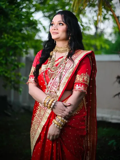 A classic pose showing the intricate details of her traditional jewelry and the rich color of her red saree, enhanced by timeless makeup.
