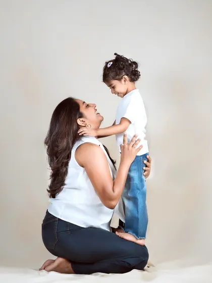 A mother and daughter share a look of pure joy and love. The simple studio setting allows their connection to be the star of the photo.