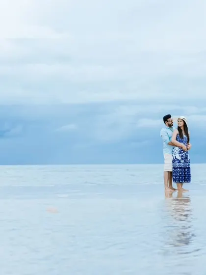 An intimate embrace during a beach pre-wedding shoot, with the soft waves and cloudy sky creating a dreamy, romantic atmosphere.