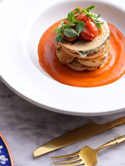 A stacked vegetable and potato gratin in a rich tomato sauce. A vegetarian delight.