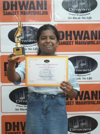 A student proudly holds her certificate and trophy.