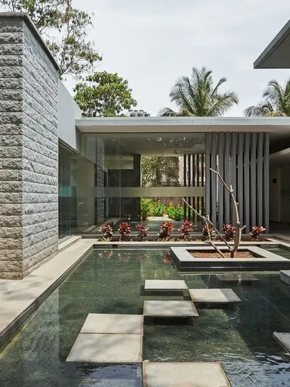 The canteen and OPD block at KIPCER, connected by a water court. The design uses a consistent material palette of grey stone and white plaster to unify the different buildings.